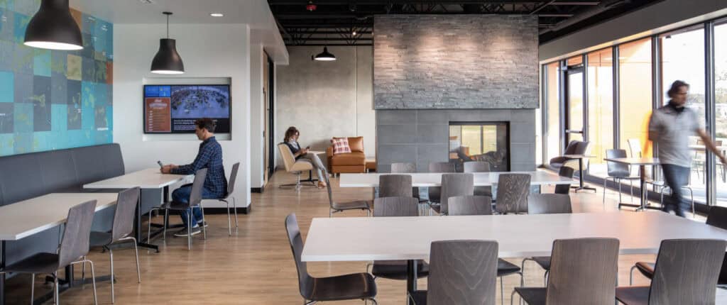 Spacious cafeteria and lounge area at Thysse's Oregon, WI headquarters, featuring a fireplace, large windows, and seating for employees.