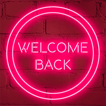 Bright pink neon sign reading 'WELCOME BACK' on a red brick wall.