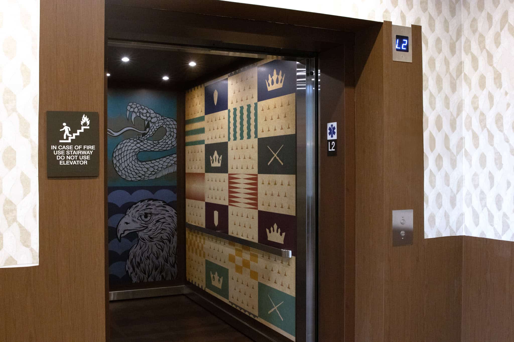 Interior of a graphic-wrapped elevator at Epic HQ, featuring crest-like banners, a snake, and an eagle in a heraldic style.
