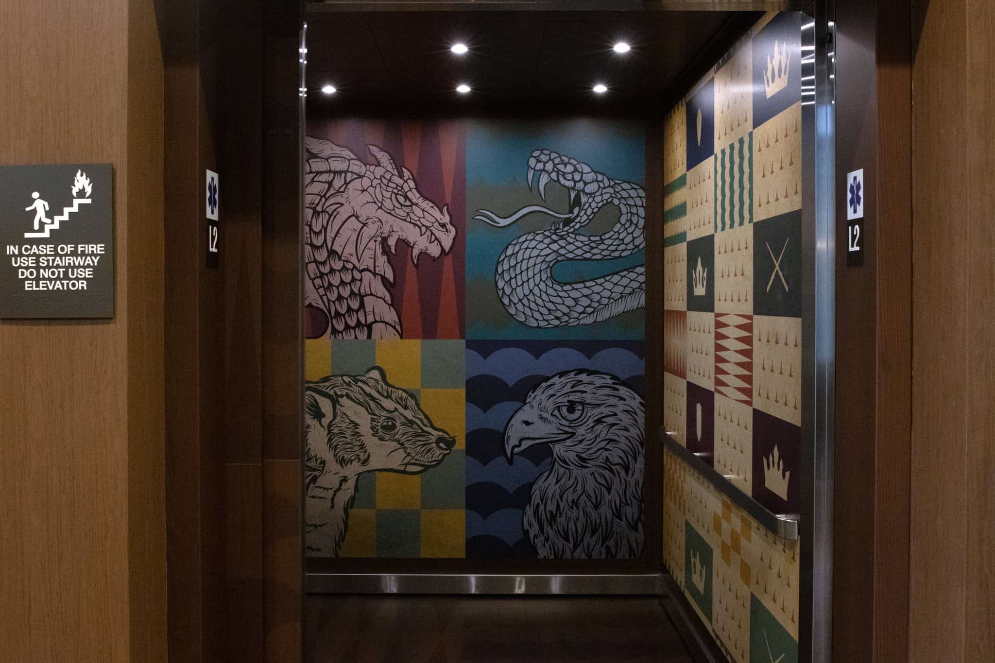 Fantasy-themed elevator interior at Epic’s Verona campus showing large illustrated creatures—a dragon, snake, badger, and eagle—along with patterned graphics.