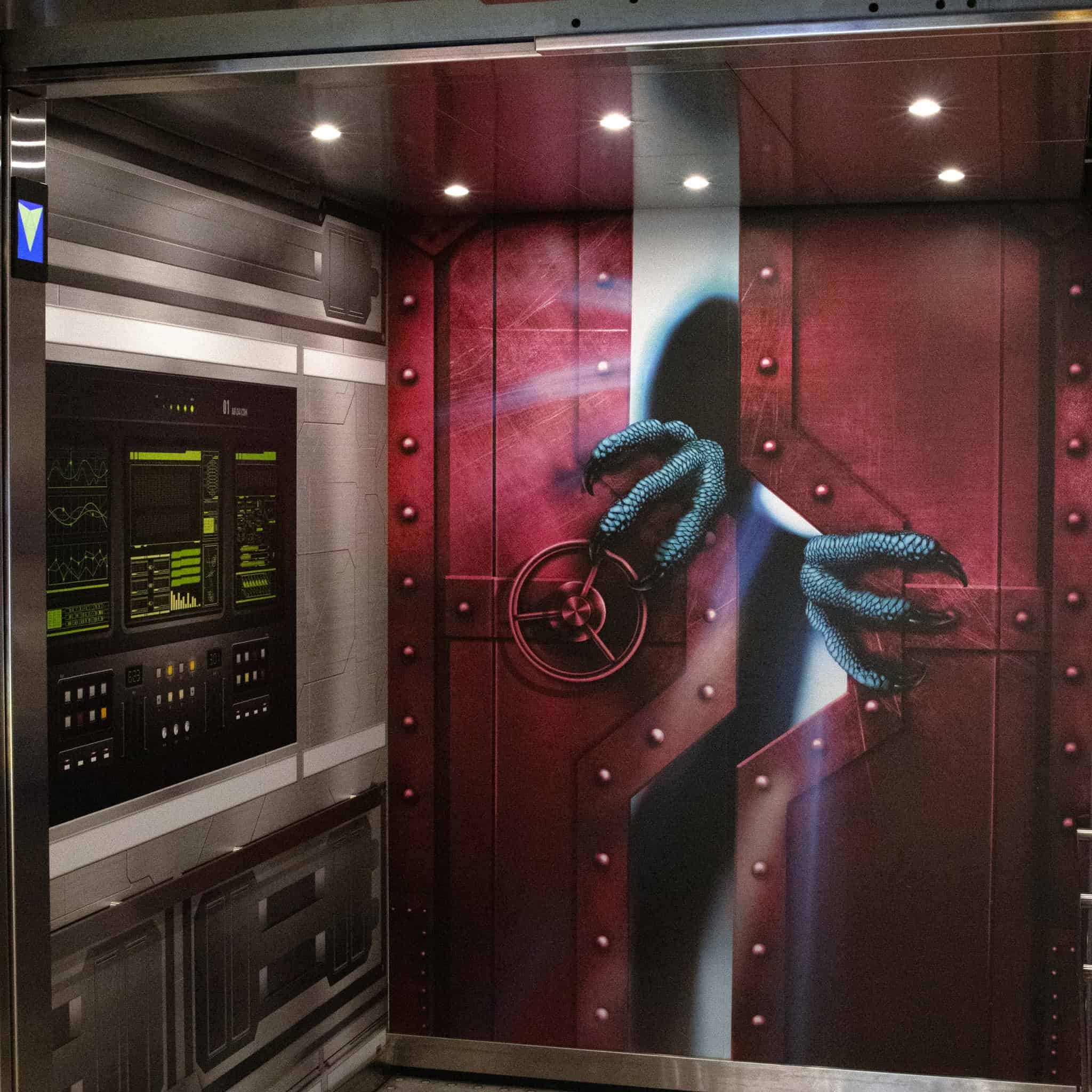 Interior of an elevator at Epic HQ with graphic design showing a sci-fi-style red metal door and blue monster claws reaching through.