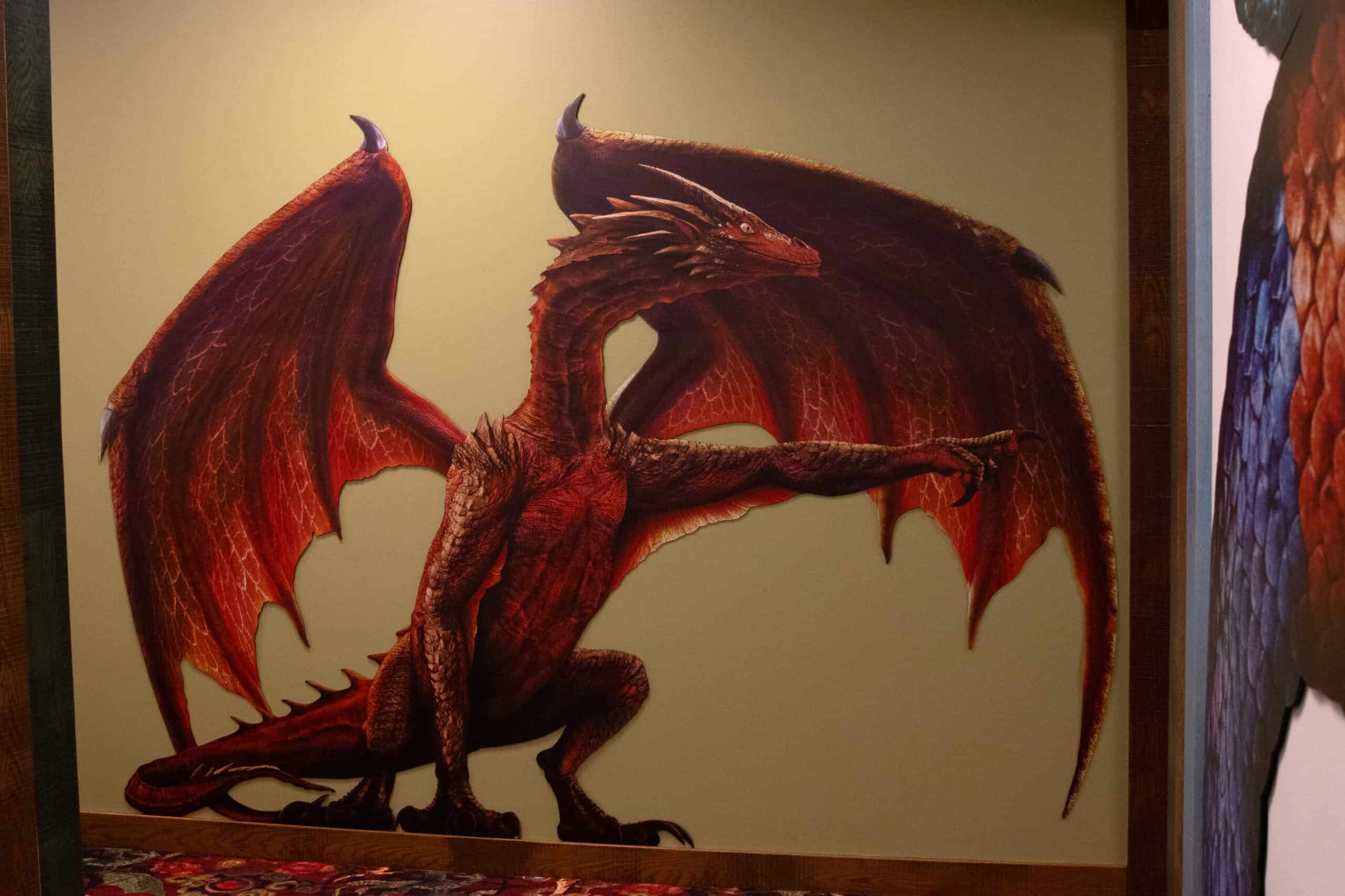 Large red dragon wall graphic at the end of a themed hallway, pointing to the left with an outstretched wing.
