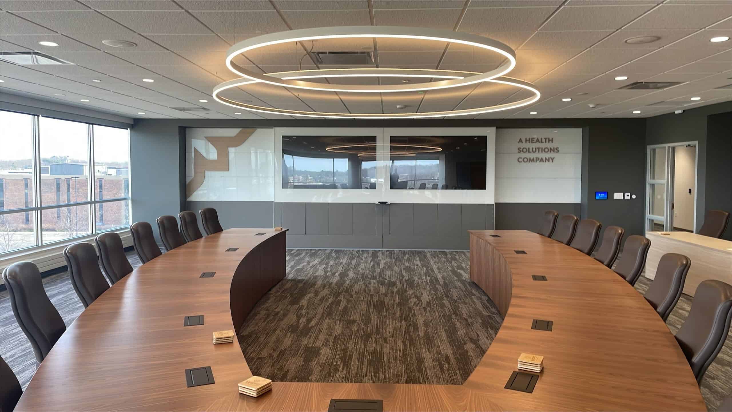 Wide-angle view of executive boardroom at WPS featuring Thysse-branded wall graphics and large wood conference table.