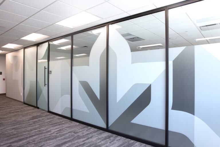 Full glass wall with custom frosted WPS brand pattern for privacy and design continuity.