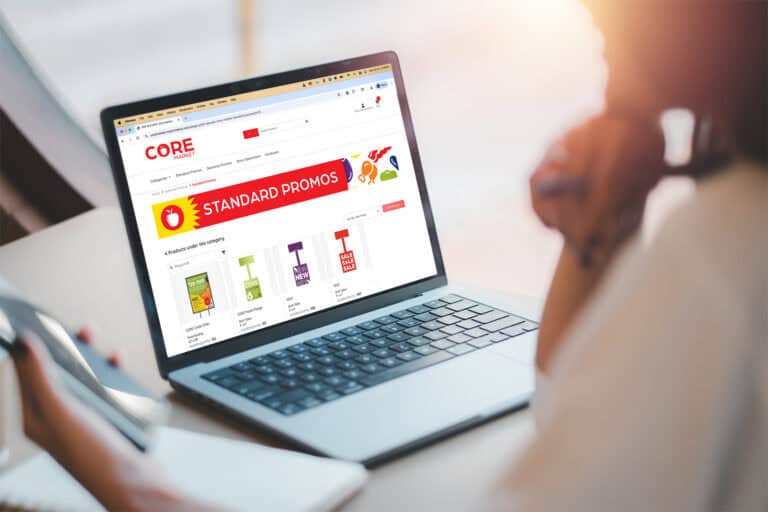 A person uses a laptop displaying Thysse’s Brand Portal, showing the CORE Market storefront page with “Standard Promos” signage products available for ordering and fulfillment.