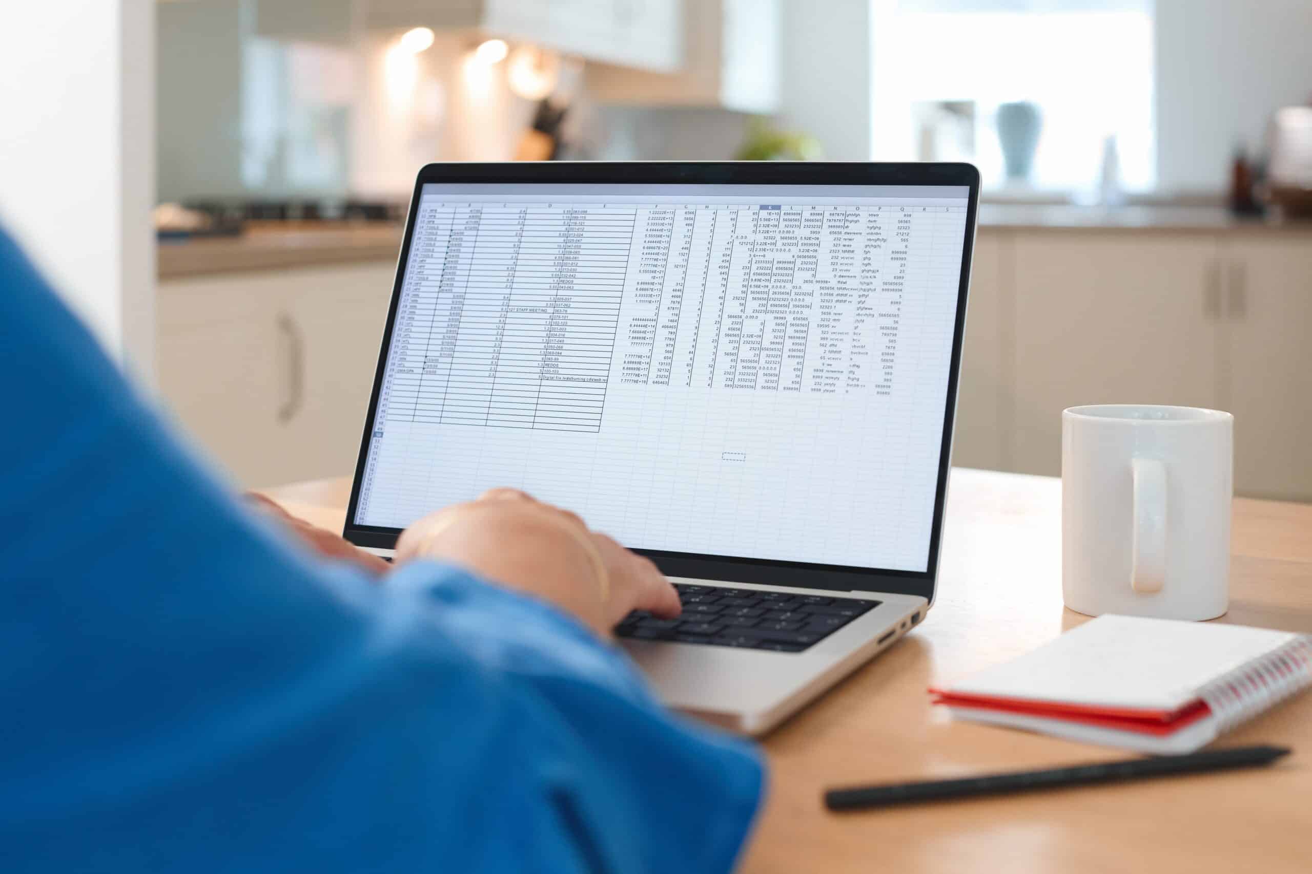Person Working on a Laptop With Data Analysis in a Bright Kitchen Space